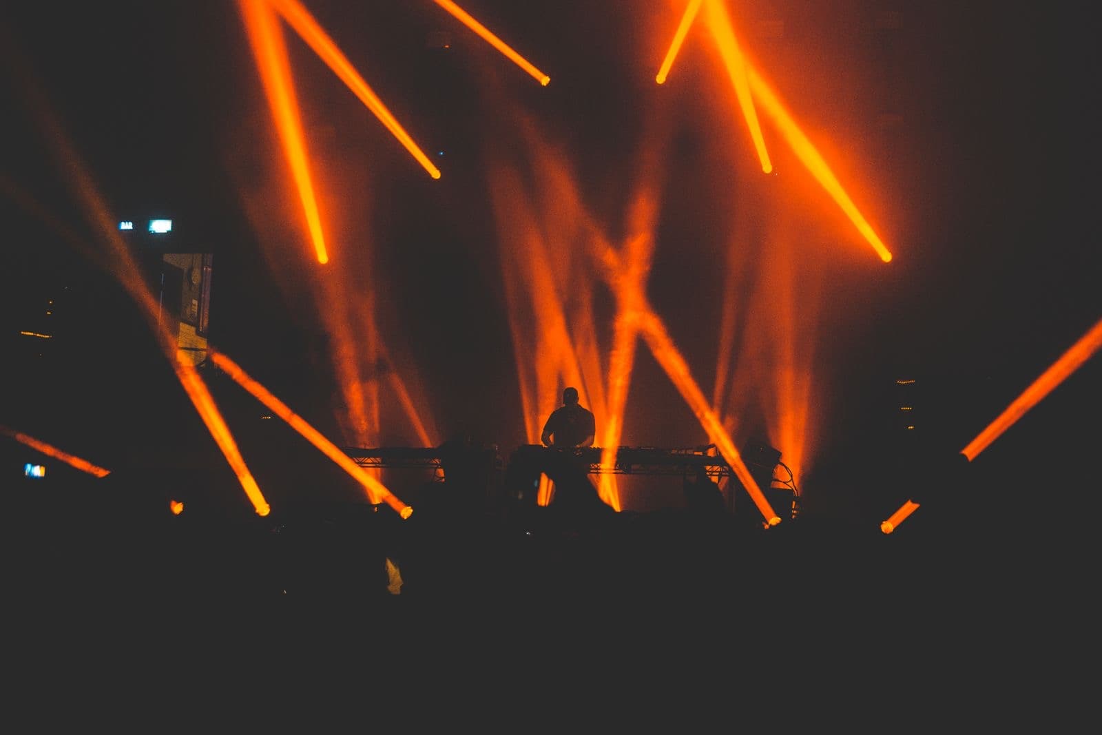 DJ silhouetted against orange light beams on a small stage